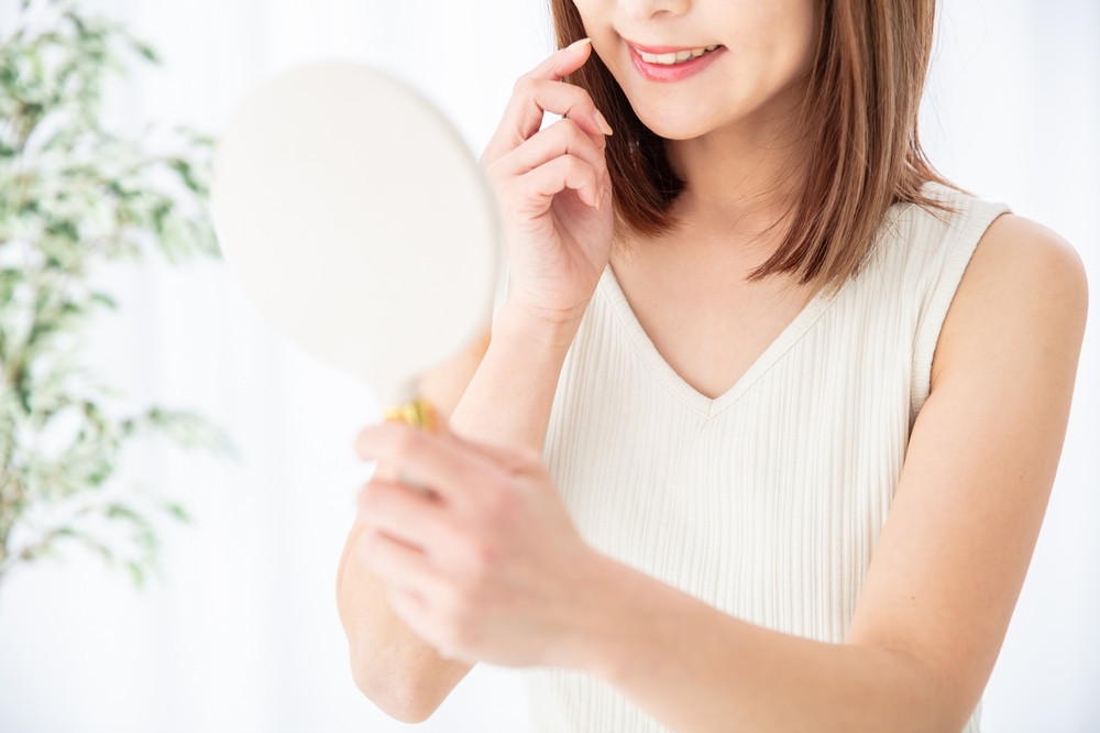 鏡で歯の色を確認する女性